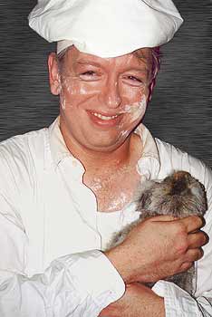 a cheery photo of the Baker smiling with flour all over his face, holding his kitten Pom Pom